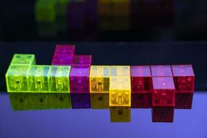 three-dimensional colored tetris figures on glossy black glass, space for copying photo