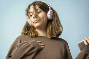 A cute European teenage girl listens to music in wireless headphones from a smartphone photo