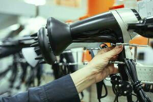 woman's hand takes a hair dryer from window of a home appliance store photo