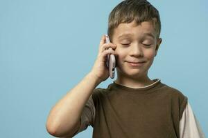 funny Caucasian boy is talking on the phone with his eyes closed with pleasure photo