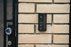 intercom panel with a video camera on the brick fence of private house photo