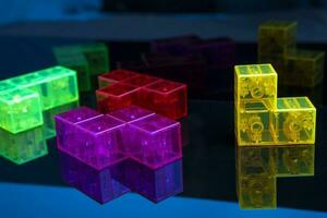 three-dimensional tetris. scattered colored tetris figures on glossy black glass, a place to copy photo