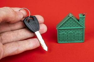 man's hand holding the key to the house, and a model of the house photo