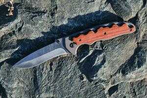 cuchillo táctico de supervivencia y protección en condiciones difíciles, en clima soleado de piedra. foto