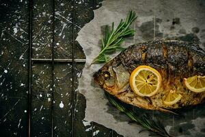 pescado horneado en horno con limón y Romero en pergamino papel, puesto fuera en rallar oscuro antecedentes. foto