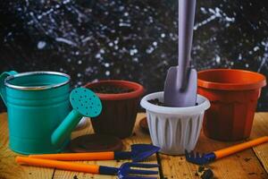 Watering can, flower pots and gardening tools on a wooden table. photo