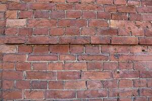 Red brick pattern. Old brick wall with cracks and scratches. Horizontal wide brickwall background. Distressed wall with broken bricks texture. Vintage house facade. photo