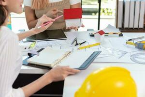 Engineers and designers are discussing the layout of the house and the construction schedule to be completed on schedule. House construction ideas with a team of professional engineers and designers. photo