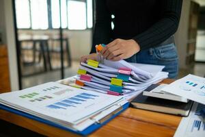 Businesswoman hands working on stacks of paper documents to search and review documents piled on table before sending them to board of directors to use  correct documents in meeting with Businessman photo