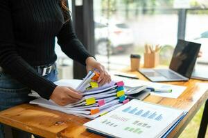 Businesswoman hands working on stacks of paper documents to search and review documents piled on table before sending them to board of directors to use  correct documents in meeting with Businessman photo