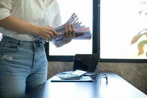 Businesswoman hands working on stacks of paper documents to search and review documents piled on table before sending them to board of directors to use  correct documents in meeting with Businessman photo