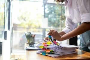 Businesswoman hands working on stacks of paper documents to search and review documents piled on table before sending them to board of directors to use  correct documents in meeting with Businessman photo