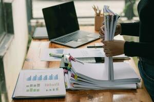 Businesswoman hands working on stacks of paper documents to search and review documents piled on table before sending them to board of directors to use  correct documents in meeting with Businessman photo