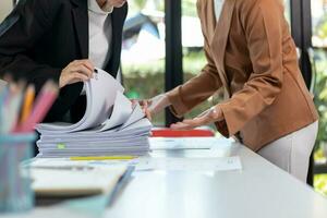 Businesswoman hands working on stacks of paper documents to search and review documents piled on table before sending them to board of directors to use  correct documents in meeting with Businessman photo