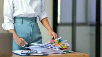 Businesswoman hands working on stacks of paper documents to search and review documents piled on table before sending them to board of directors to use  correct documents in meeting with Businessman photo