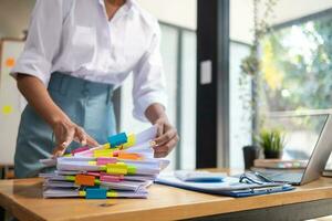 Businesswoman hands working on stacks of paper documents to search and review documents piled on table before sending them to board of directors to use  correct documents in meeting with Businessman photo