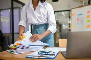 Businesswoman hands working on stacks of paper documents to search and review documents piled on table before sending them to board of directors to use  correct documents in meeting with Businessman photo