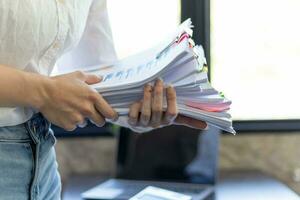 Businesswoman hands working on stacks of paper documents to search and review documents piled on table before sending them to board of directors to use  correct documents in meeting with Businessman photo