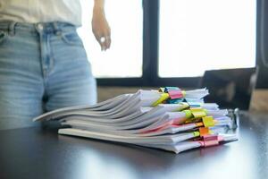 Businesswoman hands working on stacks of paper documents to search and review documents piled on table before sending them to board of directors to use  correct documents in meeting with Businessman photo