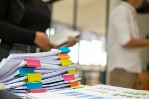Businesswoman hands working on stacks of paper documents to search and review documents piled on table before sending them to board of directors to use  correct documents in meeting with Businessman photo