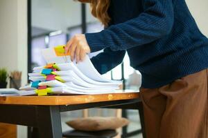 Businesswoman hands working on stacks of paper documents to search and review documents piled on table before sending them to board of directors to use  correct documents in meeting with Businessman photo