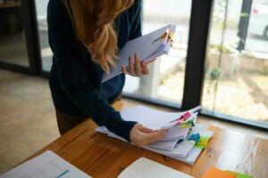 Businesswoman hands working on stacks of paper documents to search and review documents piled on table before sending them to board of directors to use  correct documents in meeting with Businessman photo