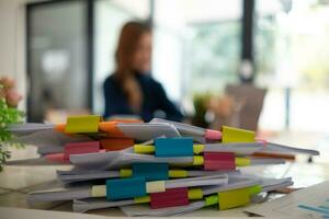 mujer de negocios manos trabajando en pilas de papel documentos a buscar y revisión documentos apilado en mesa antes de enviando ellos a tablero de directores a utilizar correcto documentos en reunión con empresario foto