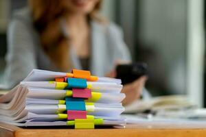 Businesswoman hands working on stacks of paper documents to search and review documents piled on table before sending them to board of directors to use  correct documents in meeting with Businessman photo