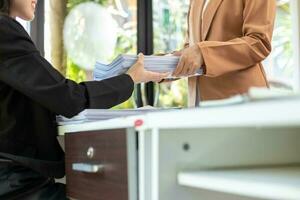 Businesswoman hands working on stacks of paper documents to search and review documents piled on table before sending them to board of directors to use  correct documents in meeting with Businessman photo