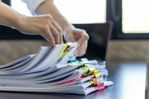 Businesswoman hands working on stacks of paper documents to search and review documents piled on table before sending them to board of directors to use  correct documents in meeting with Businessman photo