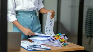 Businesswoman hands working on stacks of paper documents to search and review documents piled on table before sending them to board of directors to use  correct documents in meeting with Businessman photo