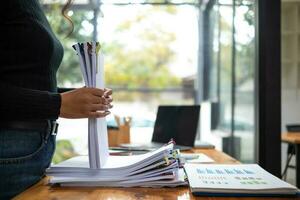 Businesswoman hands working on stacks of paper documents to search and review documents piled on table before sending them to board of directors to use  correct documents in meeting with Businessman photo