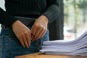 Businesswoman hands working on stacks of paper documents to search and review documents piled on table before sending them to board of directors to use  correct documents in meeting with Businessman photo