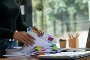 Businesswoman hands working on stacks of paper documents to search and review documents piled on table before sending them to board of directors to use  correct documents in meeting with Businessman photo