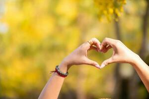 woman holds her hand above her head to form heart symbol that represents love, friendship and kindness between lovers and friends. heart symbol is concept that represents friendship, love and kindness photo