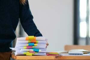 Businesswoman hands working on stacks of paper documents to search and review documents piled on table before sending them to board of directors to use  correct documents in meeting with Businessman photo