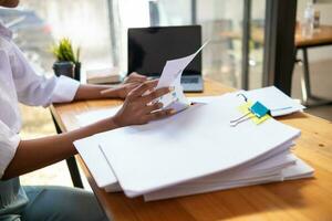 Businesswoman hands working on stacks of paper documents to search and review documents piled on table before sending them to board of directors to use  correct documents in meeting with Businessman photo