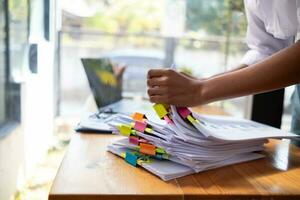 Businesswoman hands working on stacks of paper documents to search and review documents piled on table before sending them to board of directors to use  correct documents in meeting with Businessman photo