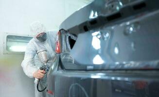 Auto mechanic in car spray room Use a spray nozzle Injected to the side of the car body with care to create beauty that blends with the original color of the car. photo