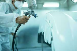 Auto mechanic in car spray room giving the spray nozzle injected into the car front bumper of the car with refinement in order to create beauty that blends with the original color of the car photo