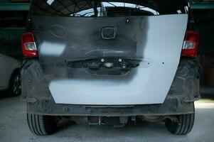 A car mechanic checks the condition of a car body to be repaired after a collision. by marking the X that need to be repaired photo