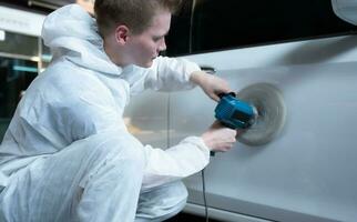 Auto mechanic use an electric polisher to polish the dried car paint. After passing the paint from the car painting room photo