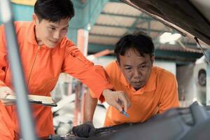 Both of auto mechanics are inspecting the engine of a customer's car being brought in for repair at a garage. photo