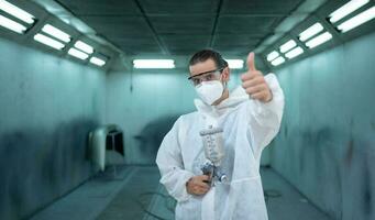 Auto mechanic in car spray room Inspecting the paint sprayed into the front bumper of the car that the pigment is complete, beautiful, harmonious with the original color of the car photo