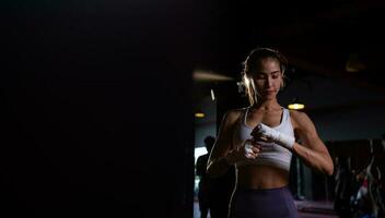 Portrait of woman learning Muay Thai to build up the strength of the body and use it for self-defense. Are using hand wraps before putting on boxing gloves for boxing photo