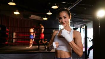 retrato de mujer aprendizaje muay tailandés a construir arriba el fuerza de el cuerpo y utilizar eso para autodefensa. son utilizando mano envuelve antes de poniendo en boxeo guantes para boxeo foto
