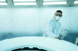 Auto mechanic in car spray room giving the spray nozzle injected into the car front bumper of the car with refinement in order to create beauty that blends with the original color of the car photo