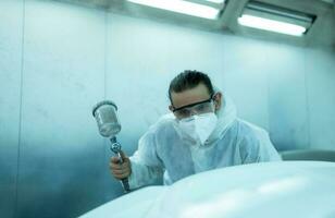 Auto mechanic in car spray room Inspecting the paint sprayed into the front bumper of the car that the pigment is complete, beautiful, harmonious with the original color of the car photo