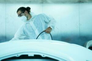 Auto mechanic in car spray room giving the spray nozzle injected into the car front bumper of the car with refinement in order to create beauty that blends with the original color of the car photo