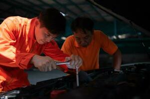 Both of auto mechanics are inspecting the engine of a customer's car being brought in for repair at a garage. photo